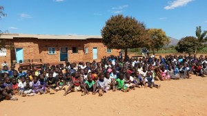 The whole school sitting outside newly painted school building